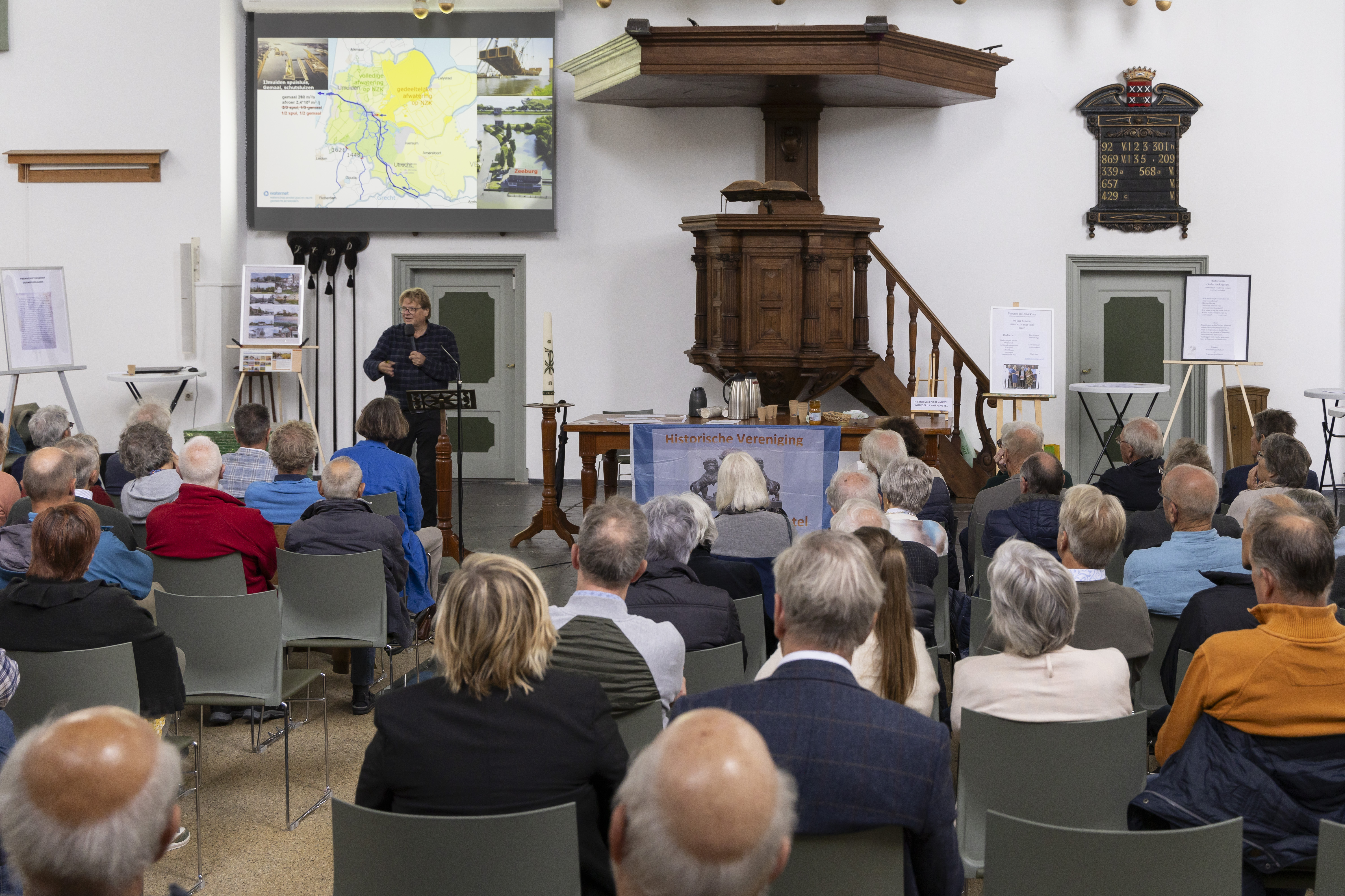 6 oktober lezing volle zaal van achteruit